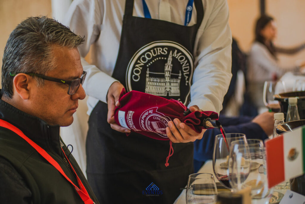 A man with glasses getting a glass of red wine