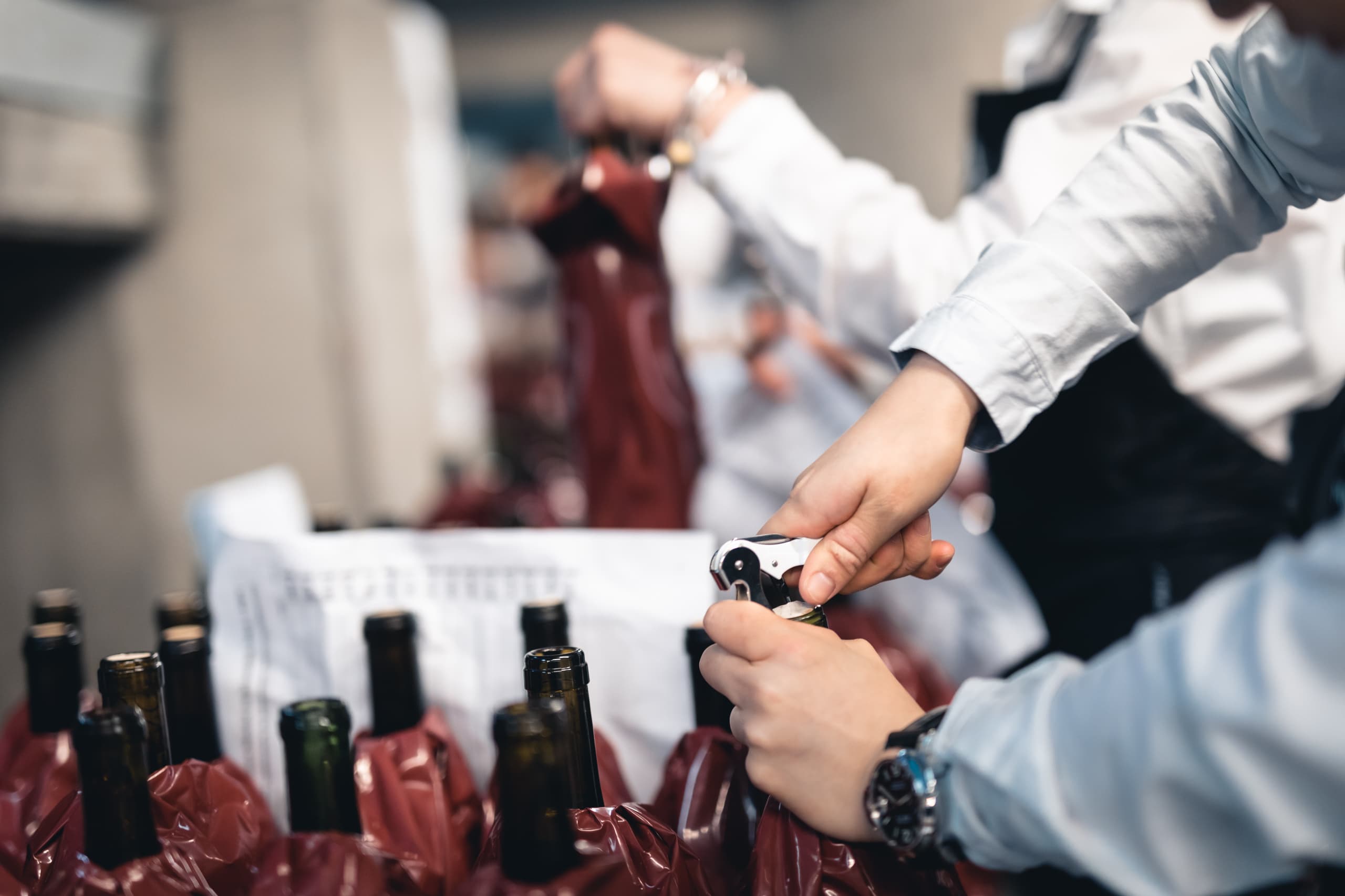 Zoom on the hand of someone uncorking a bottle of wine